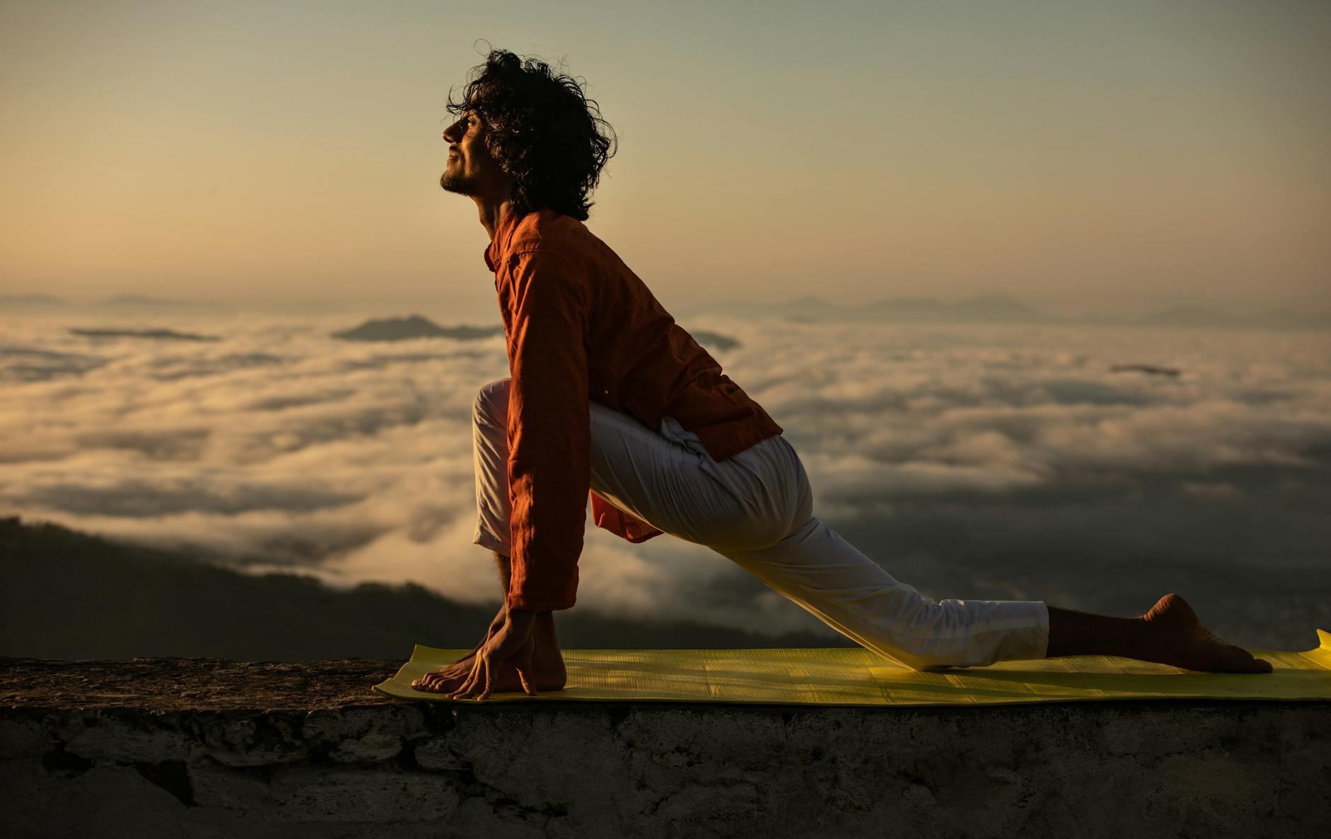 Silhouette of a person in a yoga stretch pose at sunrise.